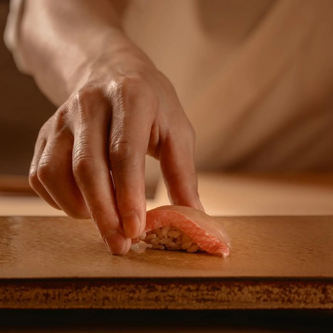 A piece of nigiri being placed on the counter at Sesui